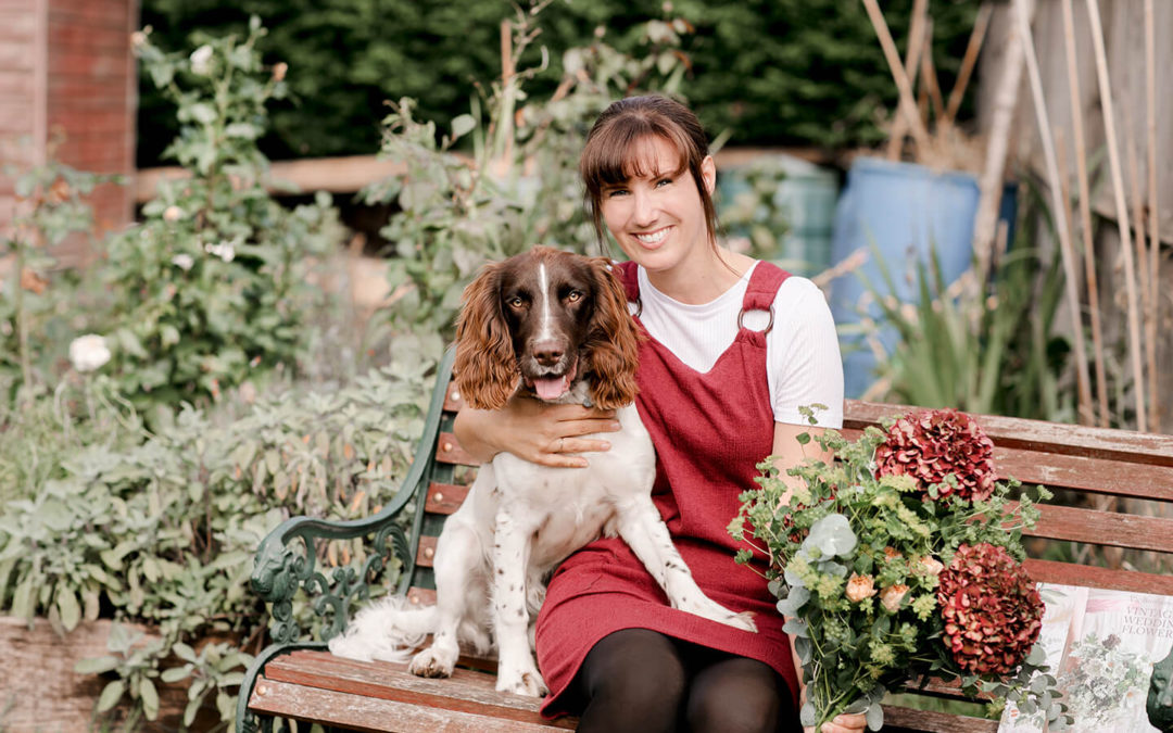 Florist with her dog in personal garden with flowers, sitting on bench, personal brand photoshoot