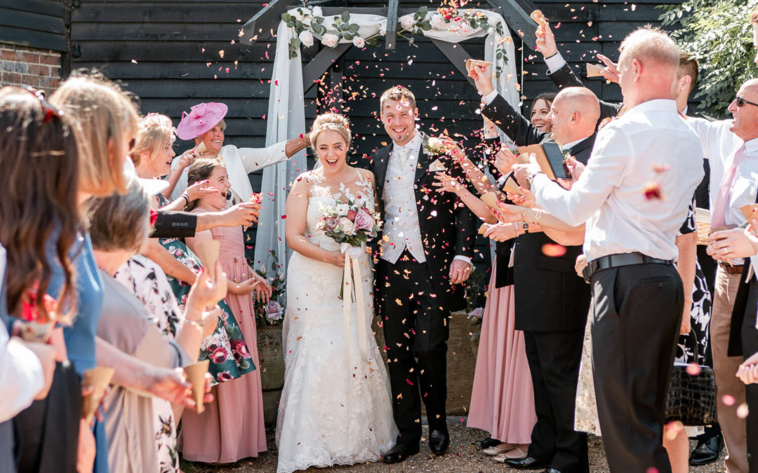 Wedding couple being greated by confetti in front of The Sussex Barn